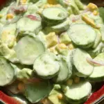 Creamy cucumber avocado salad with fresh herbs in a bowl, ideal for summer meals.